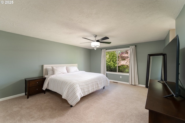 bedroom featuring baseboards, light carpet, a textured ceiling, and visible vents