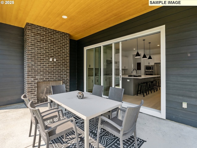 view of patio with an outdoor brick fireplace and sink