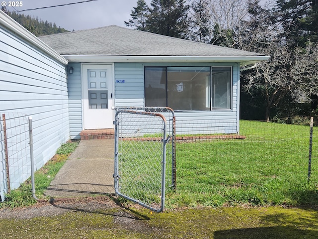 entrance to property featuring a yard and roof with shingles