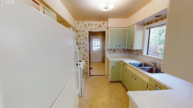 kitchen featuring light countertops, white appliances, green cabinetry, and a sink