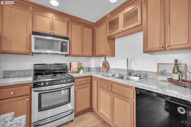 910 SE 42nd Ave Unit 370, Portland, OR 97215 - kitchen featuring appliances with stainless steel finishes, a sink, glass insert cabinets, light wood-style flooring, and light stone counters