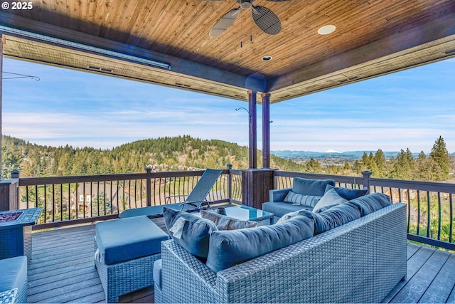 wooden terrace featuring a ceiling fan, a wooded view, and an outdoor hangout area