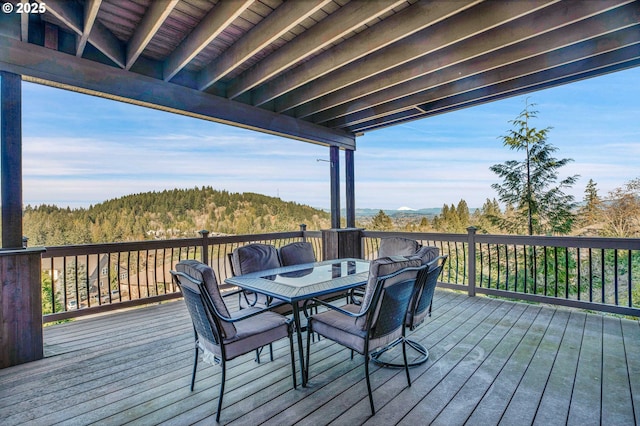 wooden deck with outdoor dining space and a wooded view