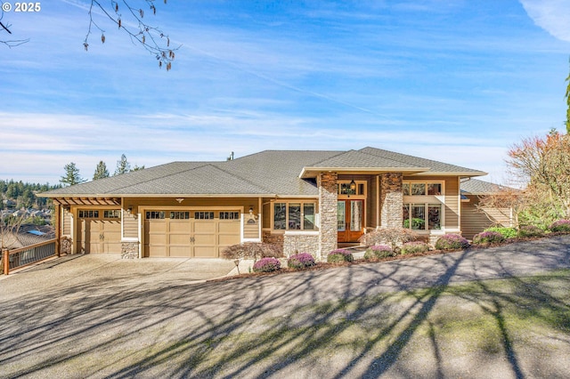 prairie-style house featuring an attached garage, stone siding, and driveway