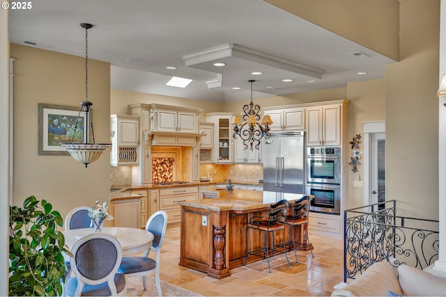 kitchen featuring visible vents, backsplash, light stone counters, cream cabinetry, and stainless steel appliances