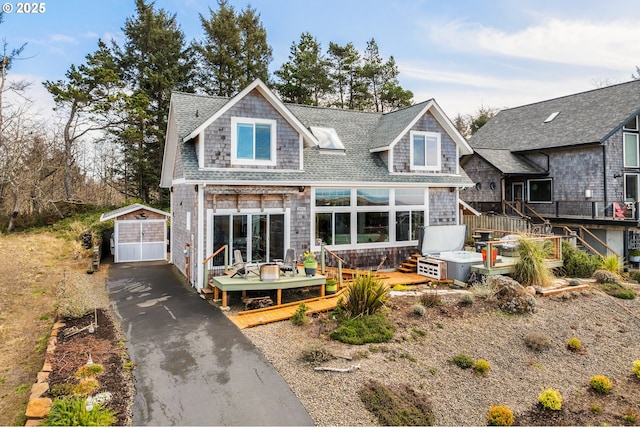 back of property featuring roof with shingles, a deck, and an outbuilding