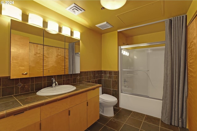 bathroom with tile patterned flooring, toilet, tile walls, enclosed tub / shower combo, and vanity