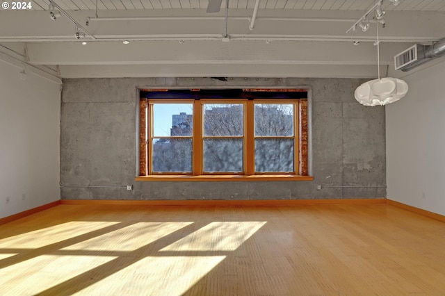 unfurnished room with track lighting, wood finished floors, and baseboards