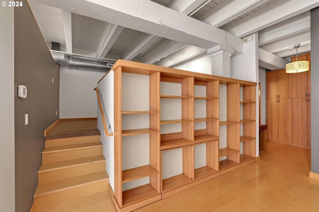 below grade area with stairs, light wood finished floors, and baseboards