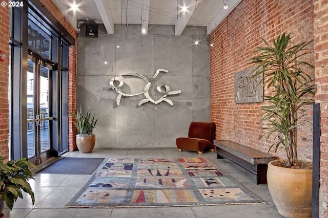 building lobby with a high ceiling, brick wall, and beamed ceiling