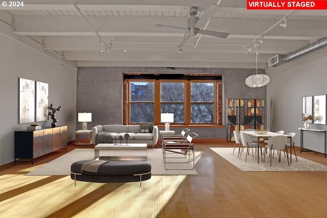 living area featuring wood finished floors, rail lighting, a ceiling fan, and baseboards