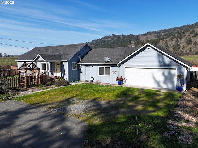 ranch-style home with fence, driveway, roof with shingles, a front lawn, and a garage