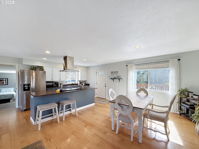 dining space with light wood finished floors, recessed lighting, a textured ceiling, and baseboards