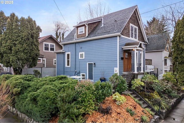 exterior space with roof with shingles and fence