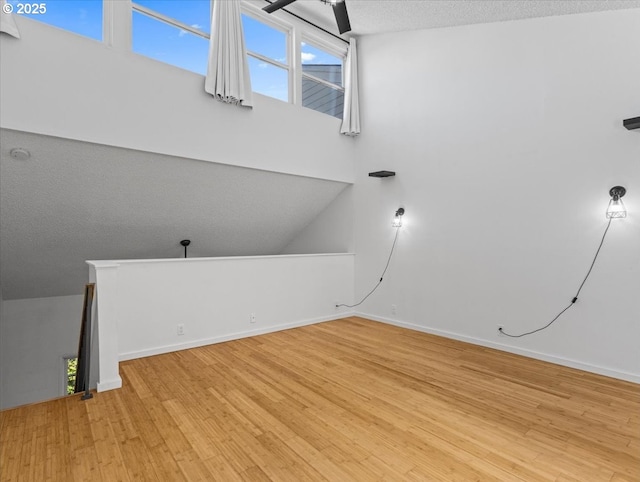 interior space featuring baseboards, a ceiling fan, wood finished floors, and a textured ceiling