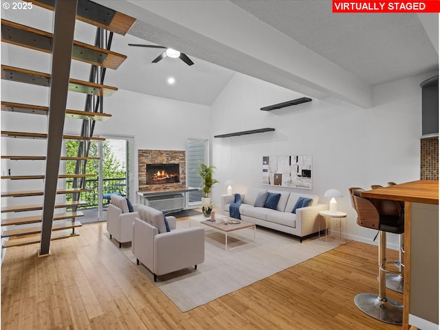 living area with baseboards, light wood-type flooring, high vaulted ceiling, and ceiling fan