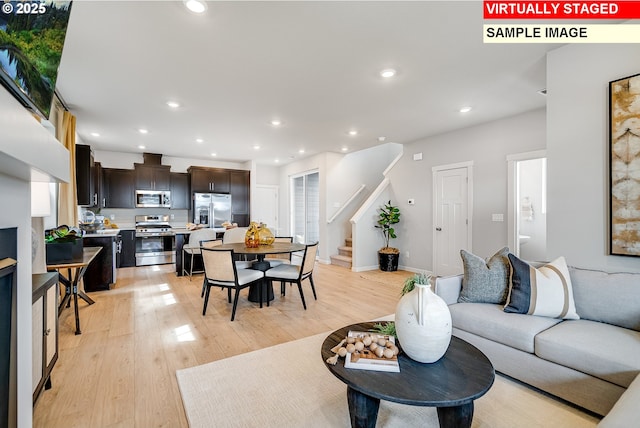 living area with light wood-type flooring, baseboards, recessed lighting, and stairs