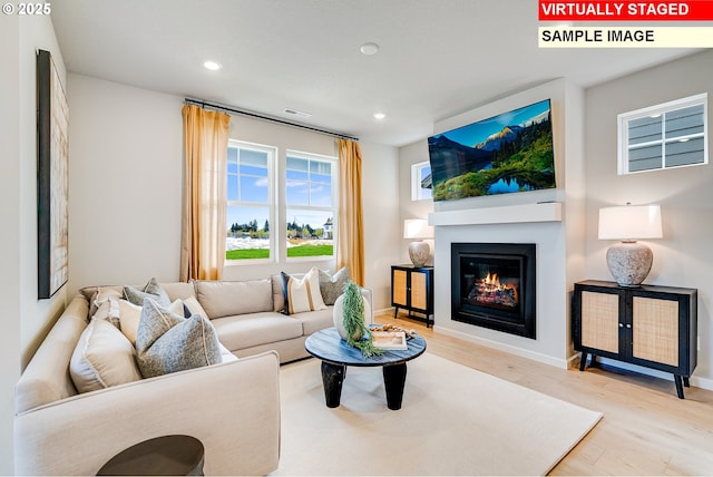 living area featuring recessed lighting, wood finished floors, visible vents, baseboards, and a glass covered fireplace