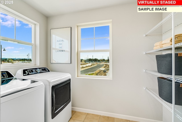 clothes washing area with light tile patterned floors, laundry area, washing machine and clothes dryer, and baseboards