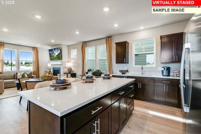 kitchen with light countertops, a glass covered fireplace, open floor plan, and stainless steel fridge