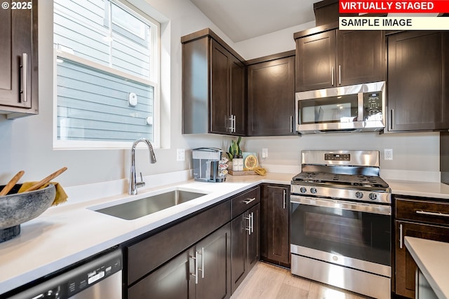 kitchen featuring appliances with stainless steel finishes, dark brown cabinets, a sink, and light countertops