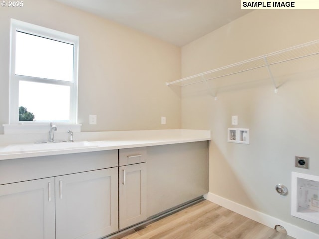 washroom featuring cabinets, electric dryer hookup, sink, light hardwood / wood-style flooring, and hookup for a gas dryer