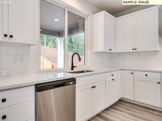 kitchen with backsplash, sink, stainless steel dishwasher, light wood-type flooring, and white cabinetry