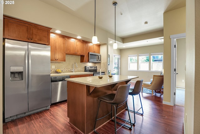13885 SW Meridian St Unit 135, Beaverton, OR 97005 - kitchen featuring stainless steel appliances, dark wood-style floors, a center island, decorative backsplash, and a breakfast bar area