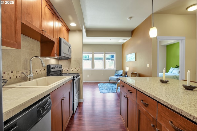 13885 SW Meridian St Unit 135, Beaverton, OR 97005 - kitchen featuring stainless steel appliances, dark wood-style floors, tasteful backsplash, hanging light fixtures, and brown cabinetry