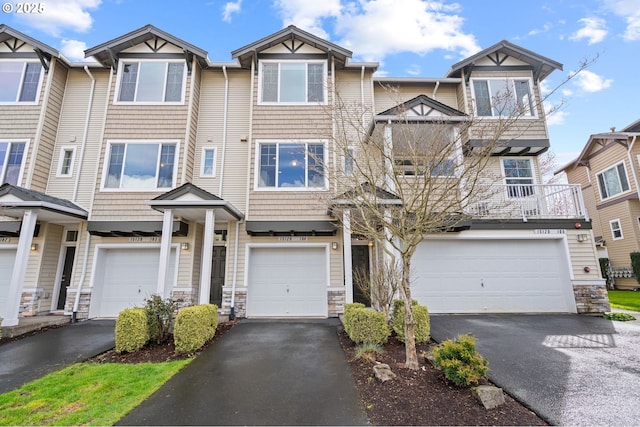 multi unit property featuring a garage, stone siding, and driveway