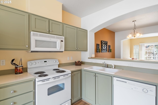 kitchen featuring white appliances, a sink, light countertops, green cabinets, and a notable chandelier