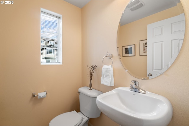 half bathroom featuring toilet, visible vents, and a sink