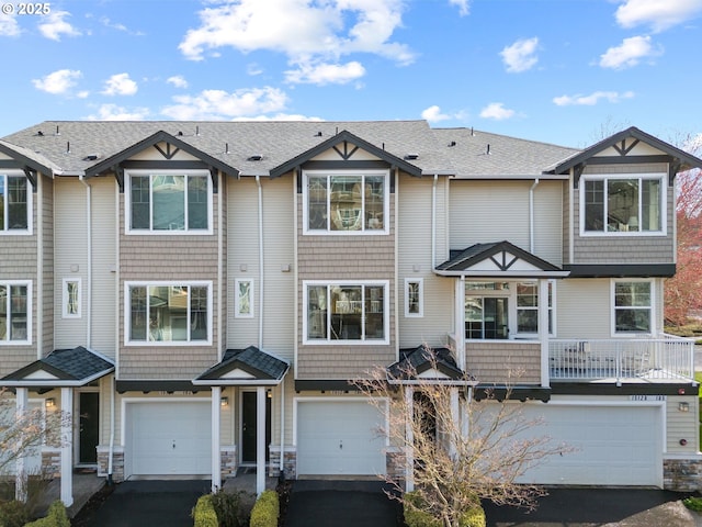 multi unit property with stone siding, driveway, and a garage