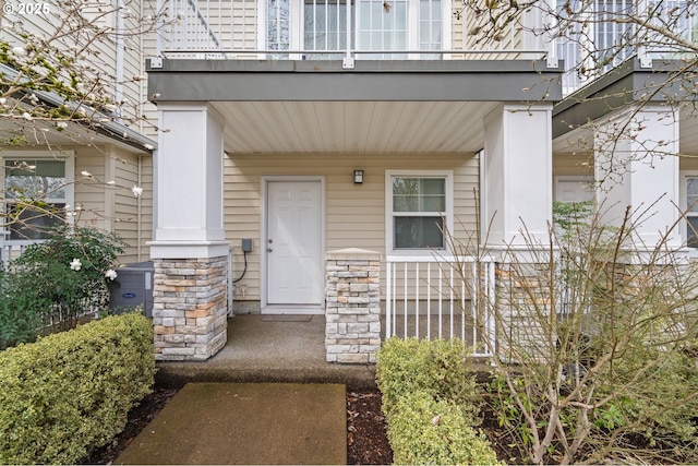 view of exterior entry featuring a balcony and covered porch