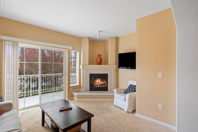 living room with visible vents, plenty of natural light, carpet floors, and a glass covered fireplace