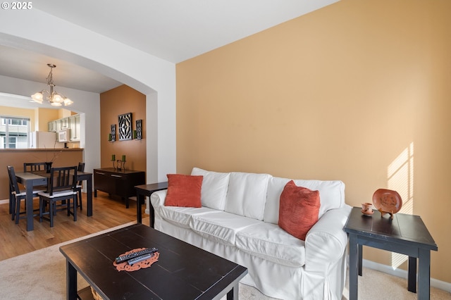 living room featuring baseboards, arched walkways, and a chandelier