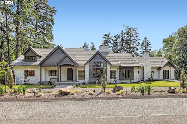 view of front of home with a front lawn, stone siding, and a chimney