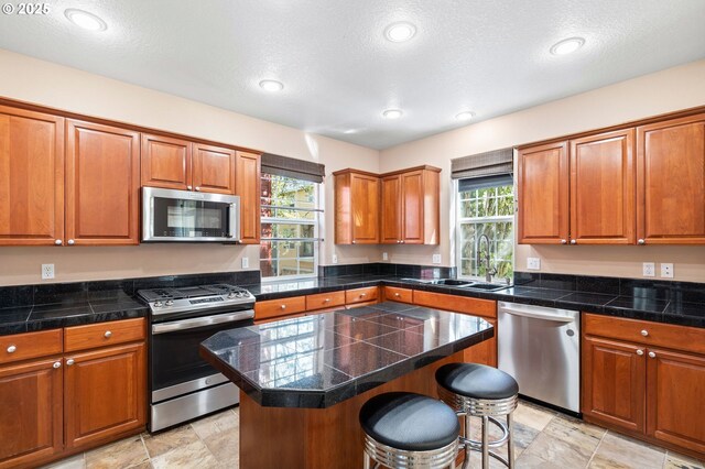 842 NE Rothbury Ave, Hillsboro, OR 97124 - kitchen featuring tile counters, a sink, brown cabinets, and appliances with stainless steel finishes