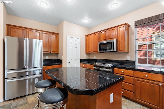 842 NE Rothbury Ave, Hillsboro, OR 97124 - kitchen featuring tile countertops, brown cabinets, appliances with stainless steel finishes, and a kitchen island