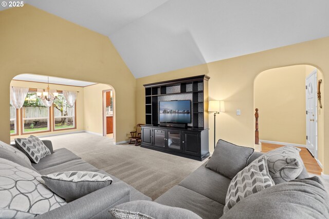 living area featuring baseboards, carpet flooring, arched walkways, a notable chandelier, and high vaulted ceiling