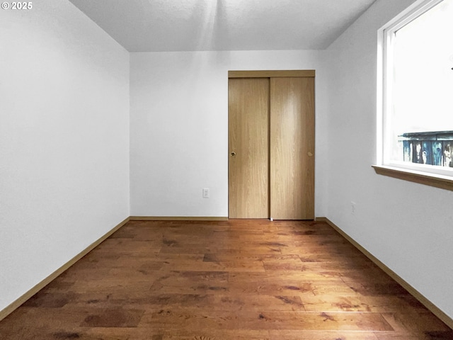 unfurnished bedroom featuring a closet, baseboards, and wood finished floors