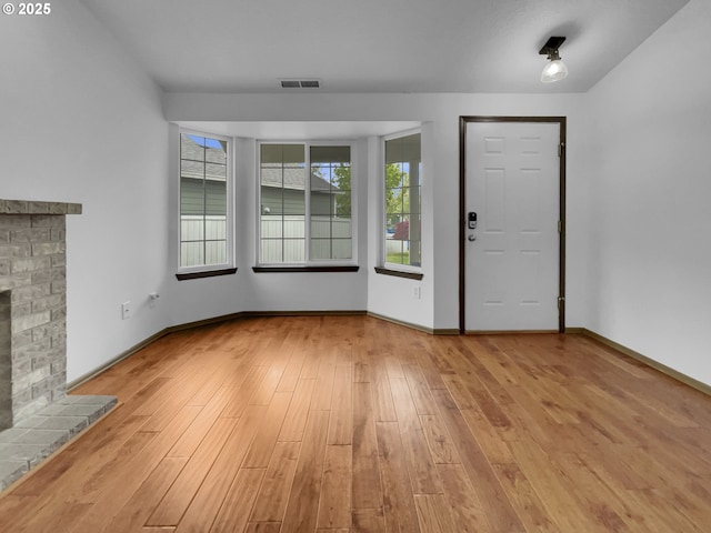 entrance foyer with visible vents, a fireplace with raised hearth, baseboards, and wood finished floors