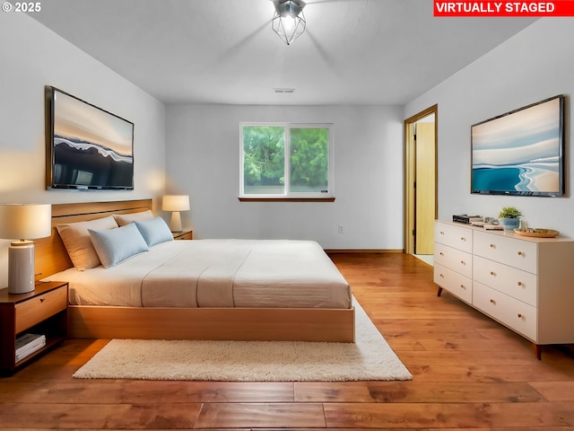 bedroom featuring baseboards, light wood-style flooring, and visible vents