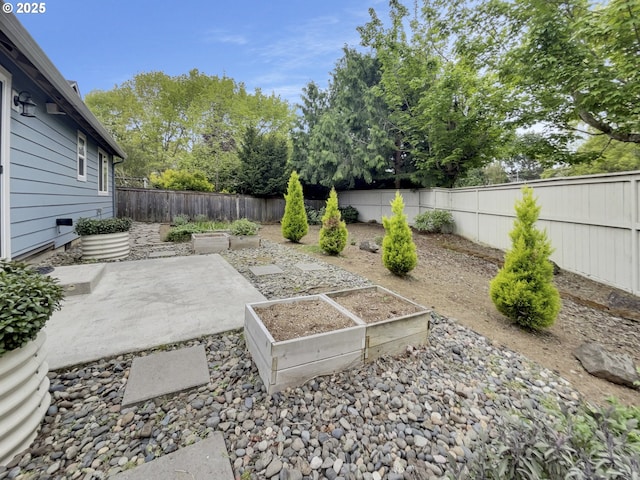 view of yard featuring a fenced backyard, a patio, and a garden
