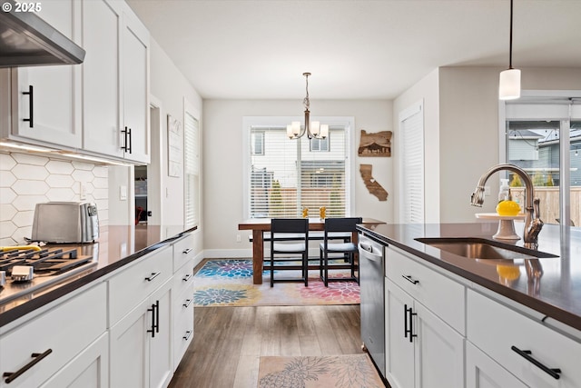 kitchen with sink, white cabinetry, hanging light fixtures, extractor fan, and stainless steel dishwasher