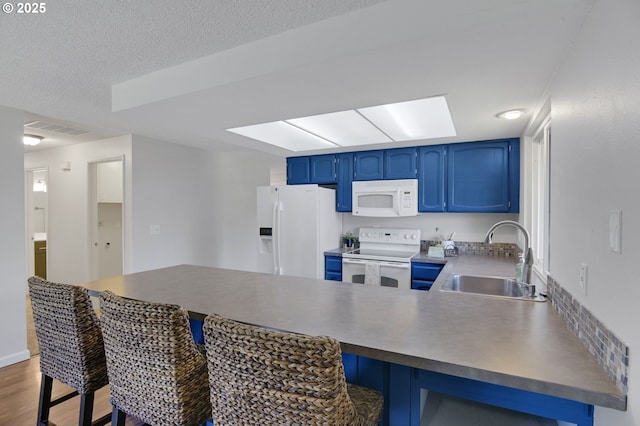kitchen with visible vents, a peninsula, white appliances, blue cabinets, and a sink