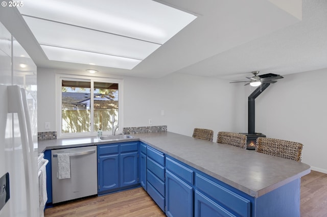 kitchen with blue cabinetry, light wood-type flooring, dishwasher, a sink, and a peninsula