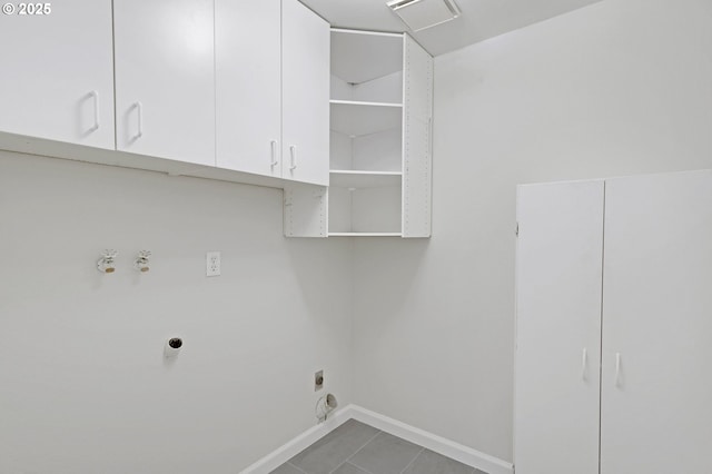 laundry room featuring electric dryer hookup, visible vents, cabinet space, baseboards, and tile patterned floors