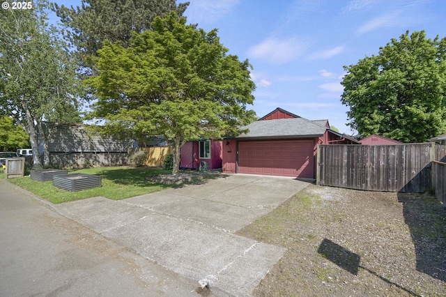 view of front of house with fence, an attached garage, concrete driveway, and a front lawn