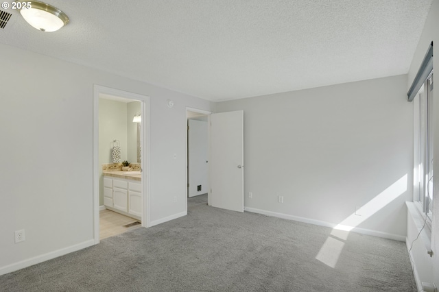 unfurnished bedroom with light colored carpet, a textured ceiling, baseboards, and visible vents